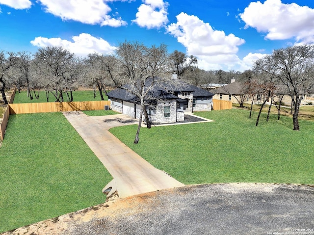 exterior space with driveway, a garage, fence, and a lawn