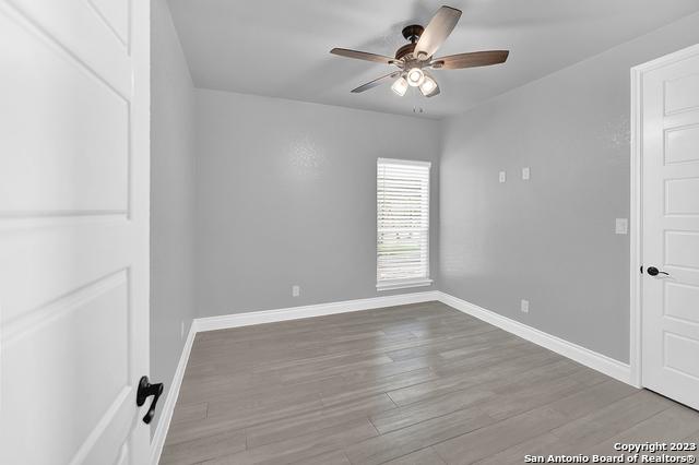 empty room featuring a ceiling fan, baseboards, and wood finished floors