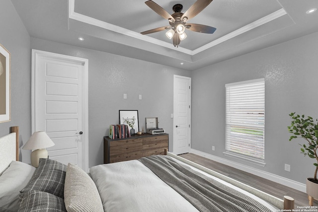 bedroom with recessed lighting, a raised ceiling, baseboards, and wood finished floors