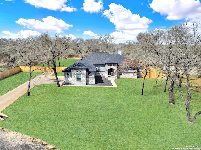 french provincial home featuring stone siding, fence, and a front lawn