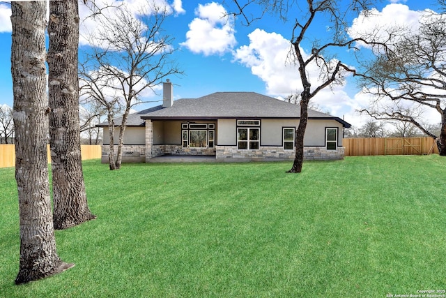 back of property with a lawn, stone siding, a chimney, fence, and stucco siding