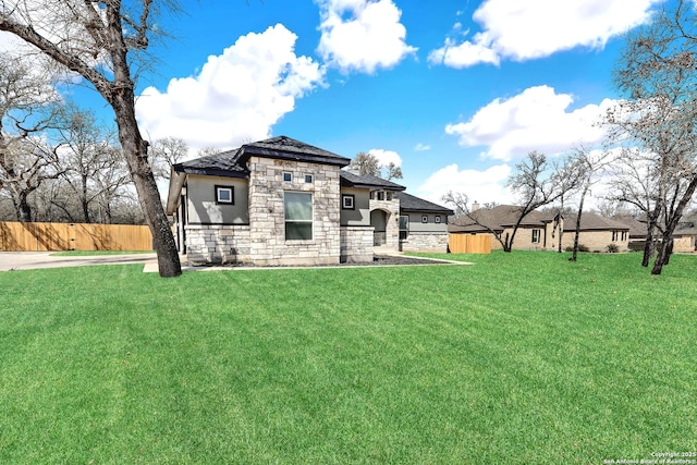 view of front of house featuring stone siding, fence, and a front lawn