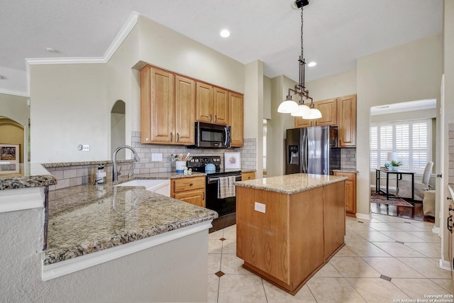 kitchen with a peninsula, light stone countertops, appliances with stainless steel finishes, and a sink