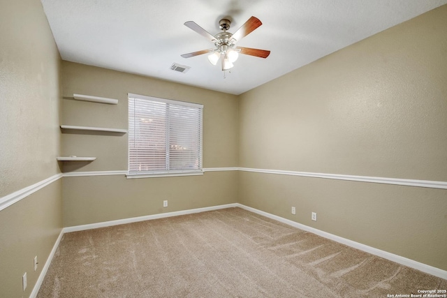 carpeted empty room with baseboards, visible vents, and a ceiling fan