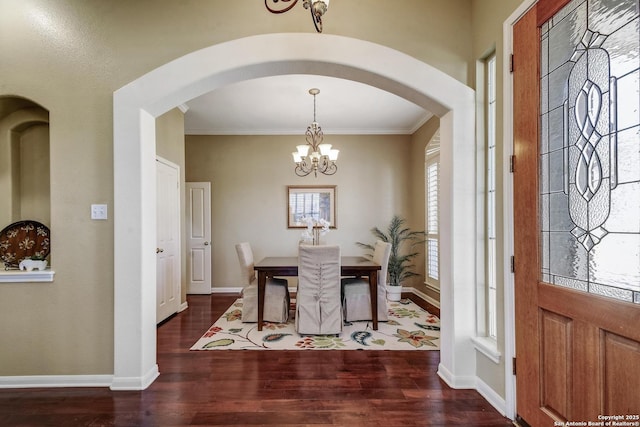 dining room featuring arched walkways, an inviting chandelier, ornamental molding, wood finished floors, and baseboards