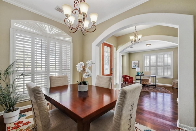 dining area with a chandelier, hardwood / wood-style flooring, visible vents, baseboards, and ornamental molding