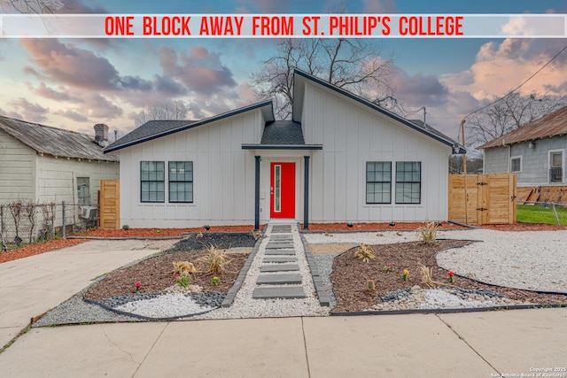 view of front facade with driveway, a shingled roof, fence, and board and batten siding