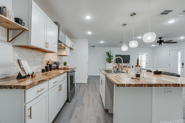 kitchen featuring butcher block countertops, a sink, electric stove, light wood finished floors, and tasteful backsplash