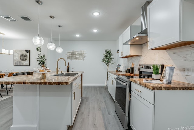 kitchen featuring butcher block countertops, a sink, visible vents, wall chimney range hood, and stainless steel electric range oven