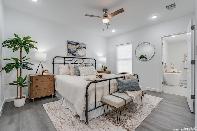 bedroom with connected bathroom, visible vents, wood finished floors, and recessed lighting