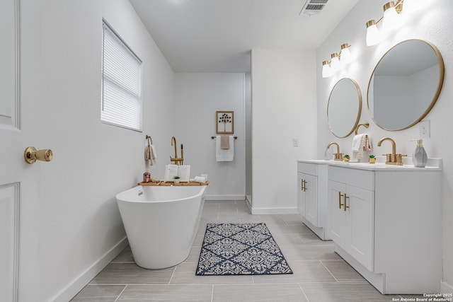 bathroom with double vanity, baseboards, visible vents, a freestanding bath, and a sink