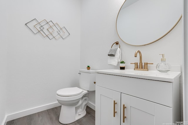 half bathroom featuring toilet, wood finished floors, vanity, and baseboards