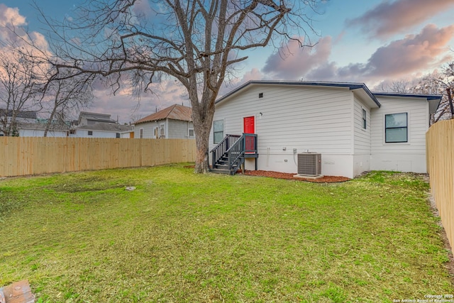 rear view of property with crawl space, a fenced backyard, a lawn, and central AC