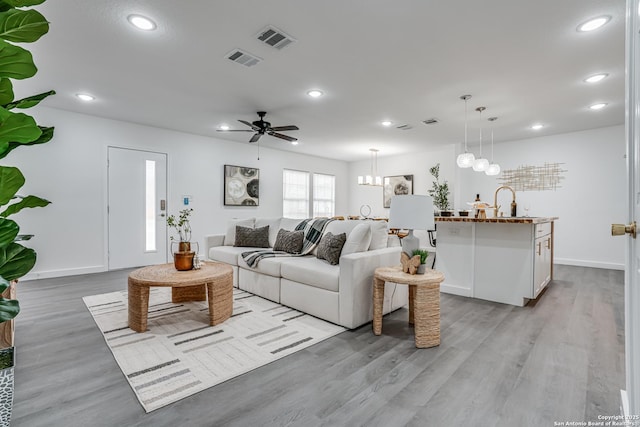 living area featuring light wood-type flooring, baseboards, visible vents, and recessed lighting