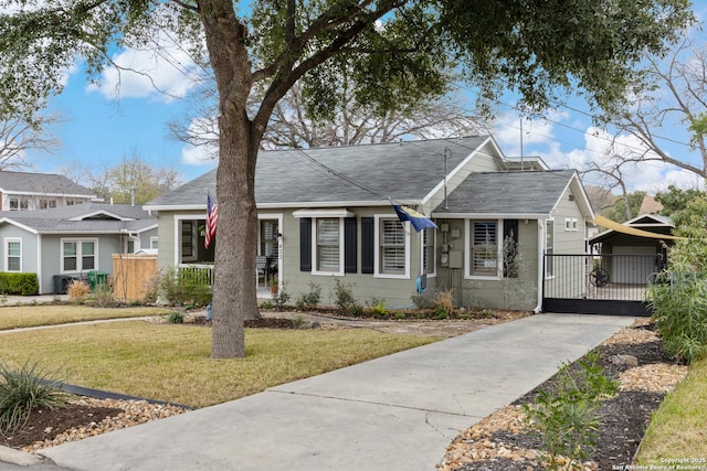 view of front of house with a shingled roof, a front yard, and a gate