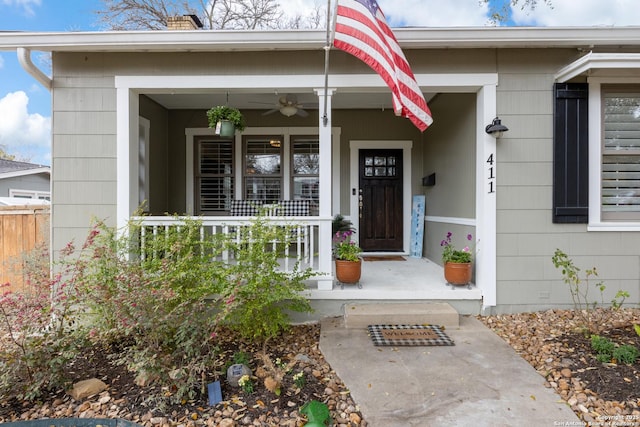 view of exterior entry with covered porch and fence