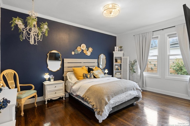 bedroom with baseboards, an accent wall, wood finished floors, crown molding, and a notable chandelier