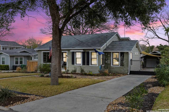 bungalow-style home featuring a yard, a shingled roof, fence, and a gate