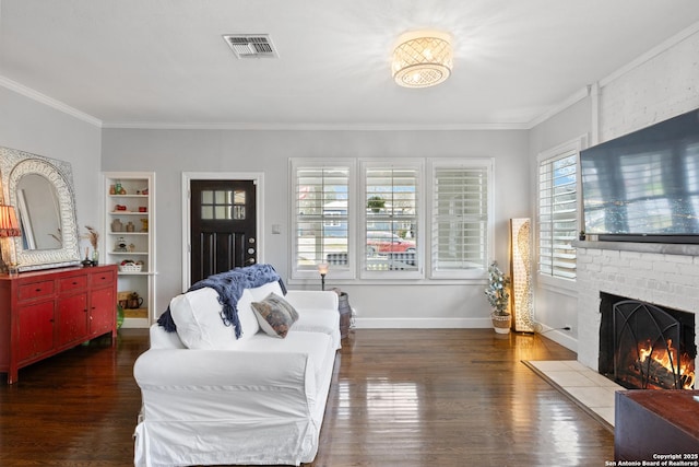 living room with a brick fireplace, visible vents, crown molding, and wood finished floors