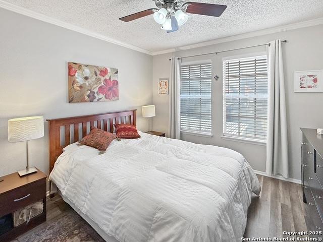 bedroom featuring crown molding, a textured ceiling, ceiling fan, and wood finished floors