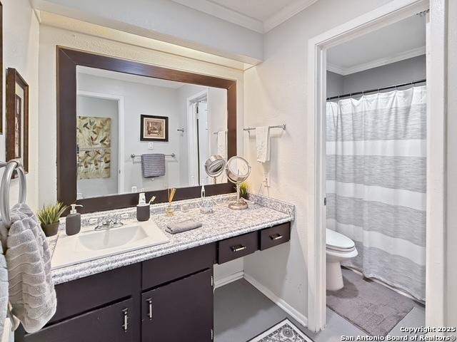 bathroom with toilet, baseboards, crown molding, and vanity