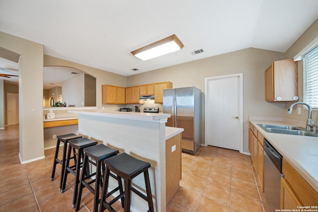 kitchen featuring visible vents, a breakfast bar, stainless steel appliances, light countertops, and a sink