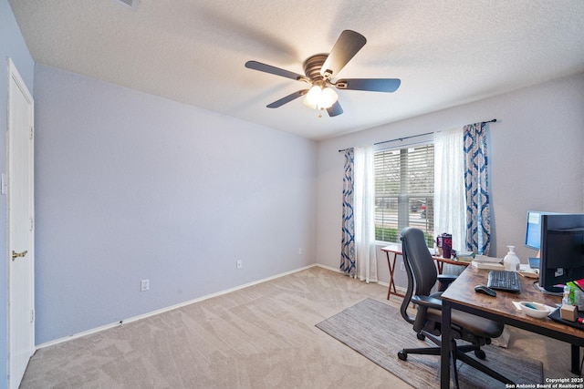 carpeted home office with a textured ceiling, baseboards, and a ceiling fan