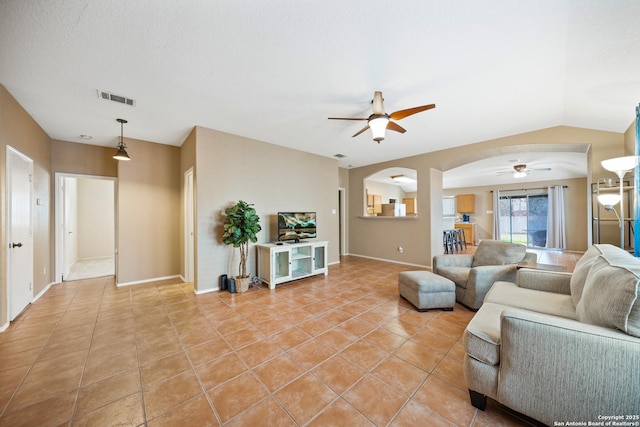 living area featuring arched walkways, light tile patterned floors, lofted ceiling, visible vents, and ceiling fan