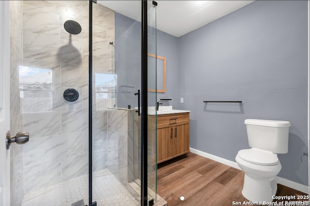 bathroom with a stall shower, baseboards, wood finished floors, and vanity