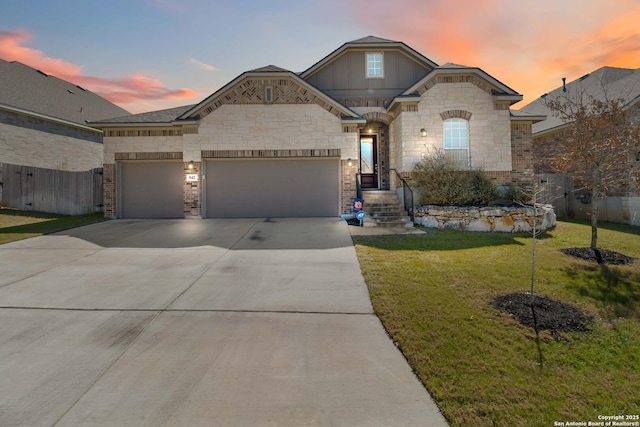 french provincial home featuring driveway, a lawn, an attached garage, fence, and brick siding