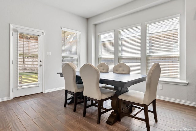 dining room with a wealth of natural light, dark wood finished floors, and baseboards