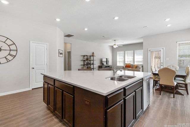 kitchen featuring dark brown cabinetry, a sink, visible vents, light wood-style floors, and stainless steel dishwasher