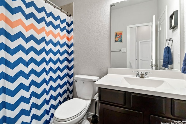 bathroom featuring a textured wall, vanity, toilet, and a shower with curtain