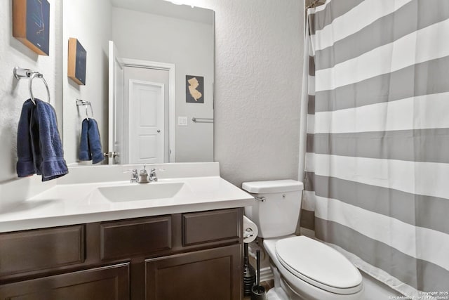 full bathroom featuring toilet, a textured wall, curtained shower, and vanity