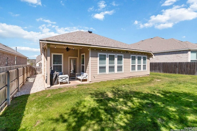 back of property with a shingled roof, a lawn, a patio, ceiling fan, and a fenced backyard