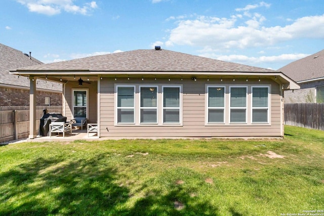 back of house featuring a ceiling fan, a fenced backyard, roof with shingles, a yard, and a patio area