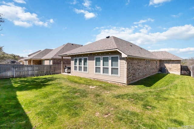 back of property featuring a yard, brick siding, and a fenced backyard