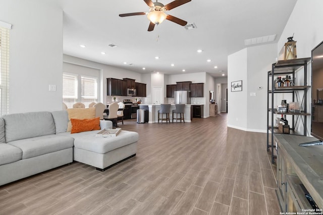 living room featuring light wood finished floors, visible vents, a ceiling fan, and recessed lighting