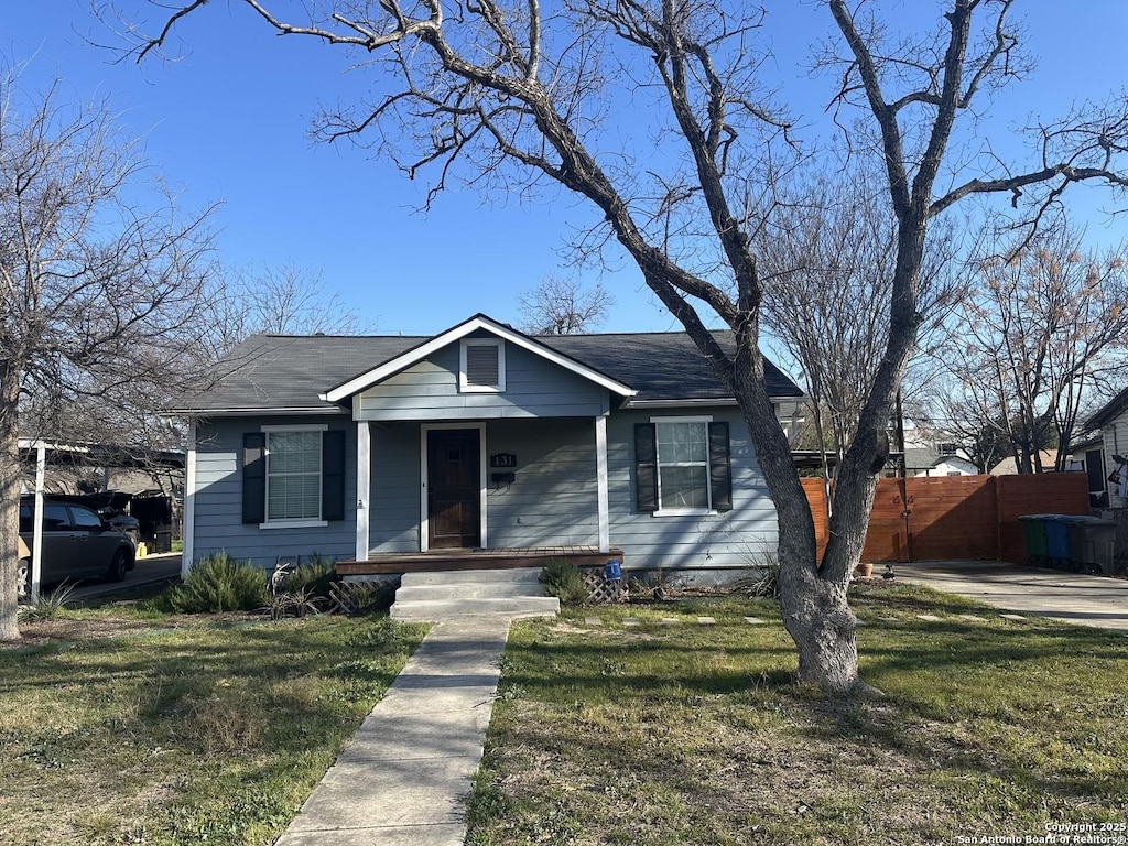 bungalow-style home with fence, a porch, and a front yard