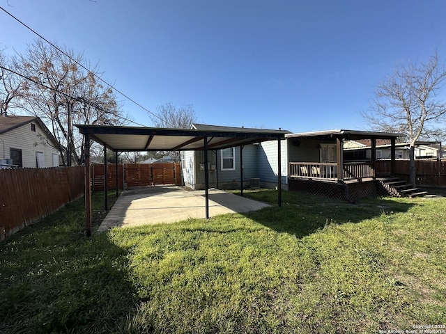 view of yard featuring a carport, a patio area, a fenced backyard, and a deck