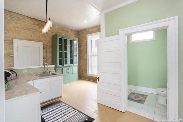 bathroom with baseboards, toilet, brick wall, wood finished floors, and vanity