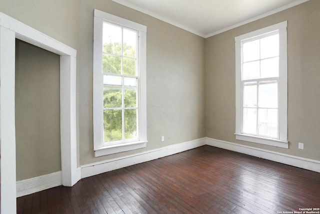 empty room with dark wood-style floors, ornamental molding, and baseboards