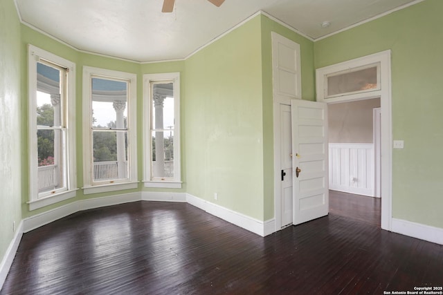 spare room featuring dark wood-style flooring, crown molding, baseboards, and ceiling fan