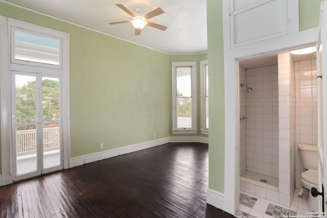 bathroom featuring a healthy amount of sunlight, toilet, a tile shower, and hardwood / wood-style floors