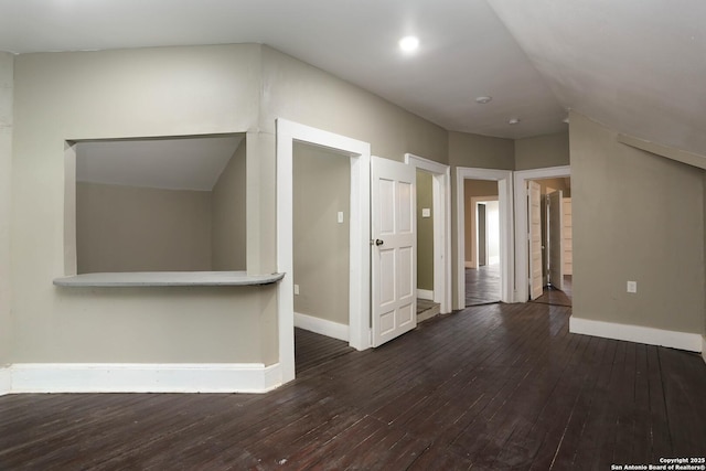 spare room with dark wood-style flooring and baseboards