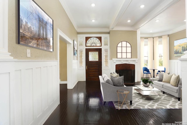 entrance foyer with dark wood-style floors, a wainscoted wall, a fireplace, and crown molding