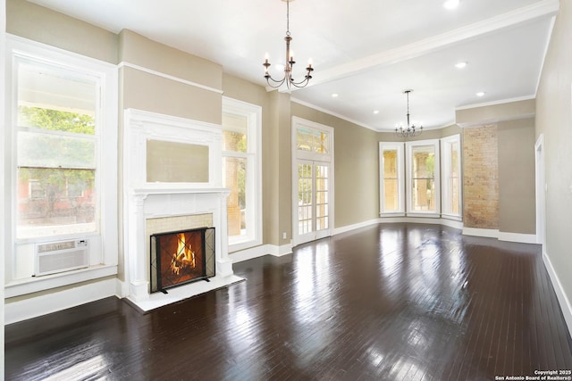 unfurnished living room with an inviting chandelier, a lit fireplace, plenty of natural light, and hardwood / wood-style floors