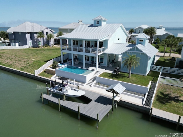 back of house with a fenced backyard, boat lift, a balcony, a water view, and a fenced in pool