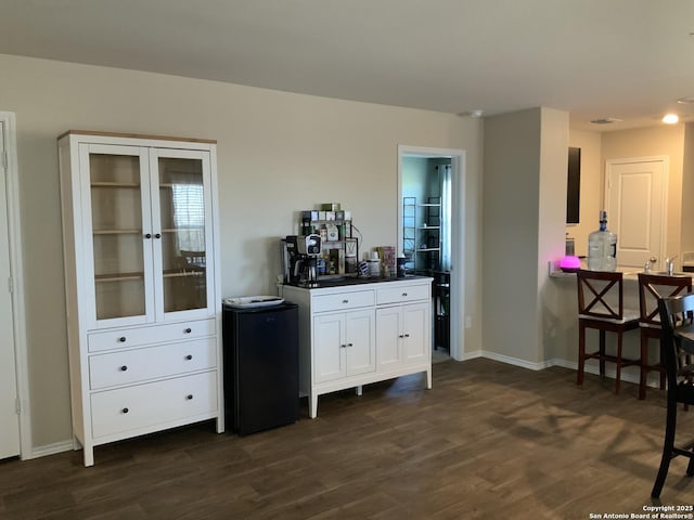 bar featuring dark wood-style floors, refrigerator, and baseboards