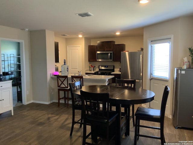 dining space featuring baseboards, visible vents, dark wood finished floors, and recessed lighting